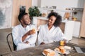 Smiling couple sitting at table with breakfast and laptop Royalty Free Stock Photo