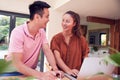 Smiling Couple Sitting At Table At Home Reviewing Domestic Finances Using Laptop Royalty Free Stock Photo