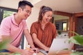 Smiling Couple Sitting At Table At Home Reviewing Domestic Finances Using Laptop Royalty Free Stock Photo