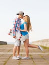 Smiling couple with skateboard kissing outdoors