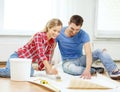 Smiling couple smearing wallpaper with glue