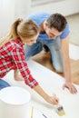 Smiling couple smearing wallpaper with glue