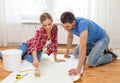 Smiling couple smearing wallpaper with glue Royalty Free Stock Photo