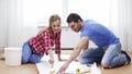 Smiling couple smearing wallpaper with glue