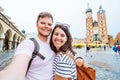smiling couple taking selfie at krakow square market church saint mary on background