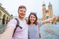 smiling couple taking selfie at krakow square market church saint mary on background