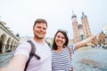 smiling couple taking selfie at krakow square market church saint mary on background