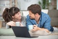 smiling couple typing on laptop at home