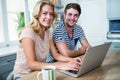 Smiling couple typing on laptop