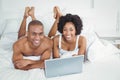 Smiling couple using laptop on bed Royalty Free Stock Photo