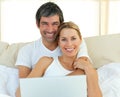 Smiling couple using a laptop lying in the bed Royalty Free Stock Photo