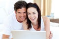 Smiling couple using a laptop lying on their bed Royalty Free Stock Photo