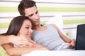 Smiling couple using a laptop lying on their bed Royalty Free Stock Photo