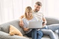 Smiling couple using laptop while sitting on the couch at home Royalty Free Stock Photo