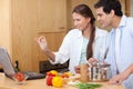 Smiling couple using a laptop to cook Royalty Free Stock Photo