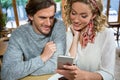 Smiling couple using mobile phone at table in cafe Royalty Free Stock Photo