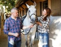 Smiling couple with white horse standing at stable outdoor Royalty Free Stock Photo