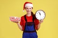 Smiling courier woman holding wrapped present box and wall clock, fast delivery service in time. Royalty Free Stock Photo