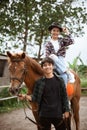 smiling cowboy girl riding horse and man holding reins