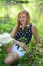 Smiling Cowgirl Sitting On Log by the Lake