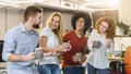 Smiling coworkers having tea during lunch break in coworking space Royalty Free Stock Photo