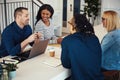 Smiling coworkers talking together at a table in an office Royalty Free Stock Photo