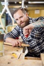 Smiling craftsman files wooden guitar neck in workshop Royalty Free Stock Photo