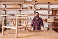 Smiling craftsman in his woodwork studio with wooden chair frame Royalty Free Stock Photo