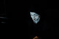 Smiling criminal anonymous mask's hacker trying to approach data. Surmise. Royalty Free Stock Photo
