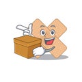 A smiling cross bandage cartoon mascot style having a box