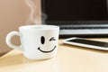 Smiling cup, smartphone and laptop on the desk