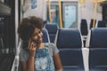 Smiling curly black girl in train using smart phone