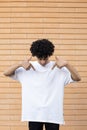Smiling curly haired African-American guy looking and pointing his fingers at his white t-shirt