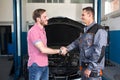 Smiling customer and mechanic shaking hands