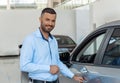 Smiling customer opening the doorknob of his own just bought car at the dealership Royalty Free Stock Photo