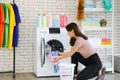 A smiling and cute Asian woman carrying a laundry basket and posing beside the washing machine Royalty Free Stock Photo