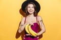 Smiling cute girl in beach hat and swimsuit holding bananas Royalty Free Stock Photo