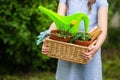 Smiling cute girl gardener holding basket and horticultural tools in garden on sunny day. Happy childhood. Summer activities Royalty Free Stock Photo