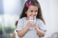 Smiling cute girl holding glass of water at home