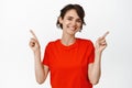 Smiling cute girl pointing fingers sideways, left and right sides, showing advertisements, white background Royalty Free Stock Photo