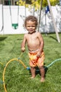 Smiling Cute little boy splashing playing in the sprinklers in the backyard Royalty Free Stock Photo