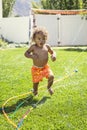 Smiling Cute little boy splashing through the sprinklers in the backyard Royalty Free Stock Photo