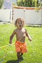 Smiling Cute little boy splashing through the sprinklers in the backyard Royalty Free Stock Photo