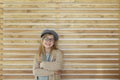 Smiling cute little girl with black eyeglasses wearing cap over wooden background Royalty Free Stock Photo