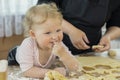 Smiling cute little girl covered in flour eating raw gingerbread cookie dough. Royalty Free Stock Photo