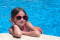 Smiling cute little girl in sunglasses in swimming pool on sunny day. Childhood and summer joy Royalty Free Stock Photo