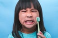 Smiling cute little girl holding toothbrush isolated on blue background. Cute little child brushing teeth. Kid training oral Royalty Free Stock Photo