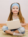 Cute little girl with a laptop at home on the floor Royalty Free Stock Photo