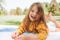 Smiling cute little girl lying on the blanket at green grass, talking with her parents. Adorable child having fun outdoors during Royalty Free Stock Photo