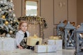 Smiling cute little girl opening a Christmas gift, the background Christmas tree Royalty Free Stock Photo